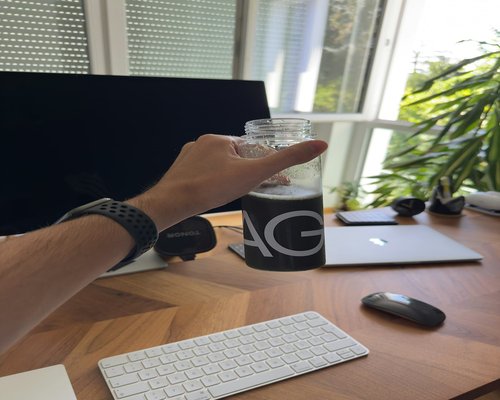 Person hydrating with a glass of water while sitting near an office desk